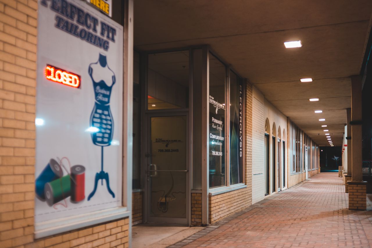 Exterior of modern boutiques with signboards and inscriptions in trading house near cobblestone pavement in night